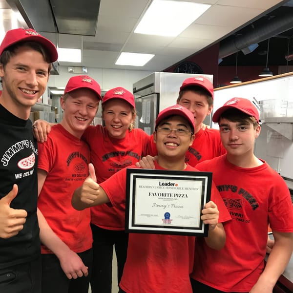 Six smiling Jimmy's Pizza employees in red shirts and hats proudly display a "Favorite Pizza" award.