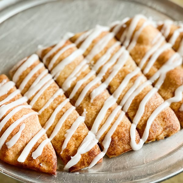 Close-up of Jimmy's Pizza cinnamon dessert pizza slices with white icing drizzle on a metal tray.
