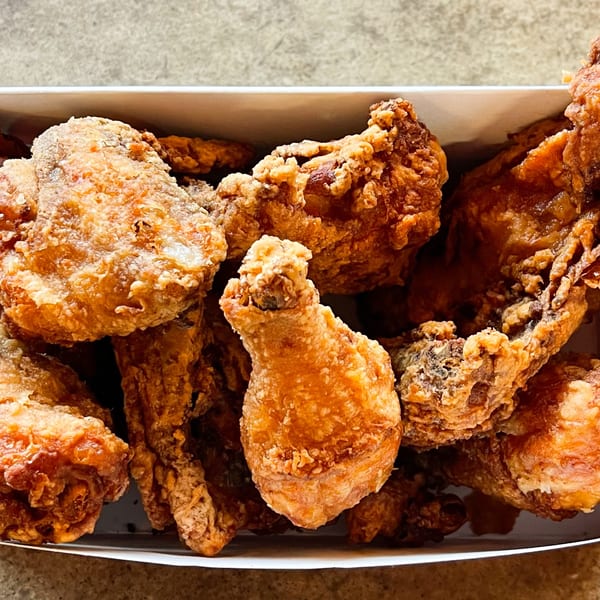 Close-up of crispy, golden-brown fried chicken pieces in a white takeout box from Jimmy's Pizza.